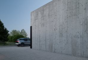 La matericità del calcestruzzo esposto definisce il carattere monolitico della villa, accentuando la semplicità formale e il forte legame con la luce naturale.