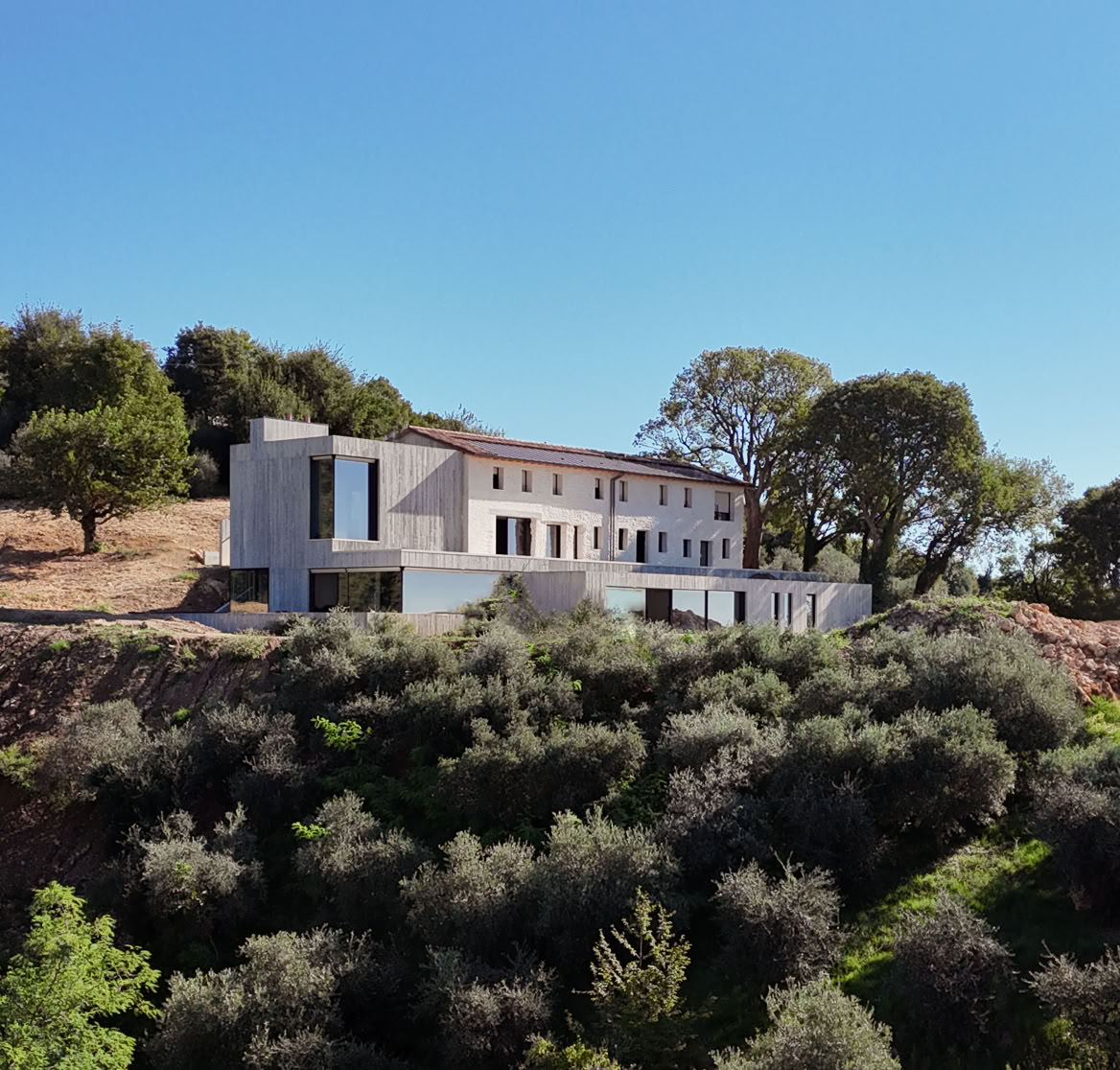 Renovated historic farmhouse in Treviso hills with contemporary expansion, panoramic views, double-height interiors, flat roof, and integrated swimming pool.