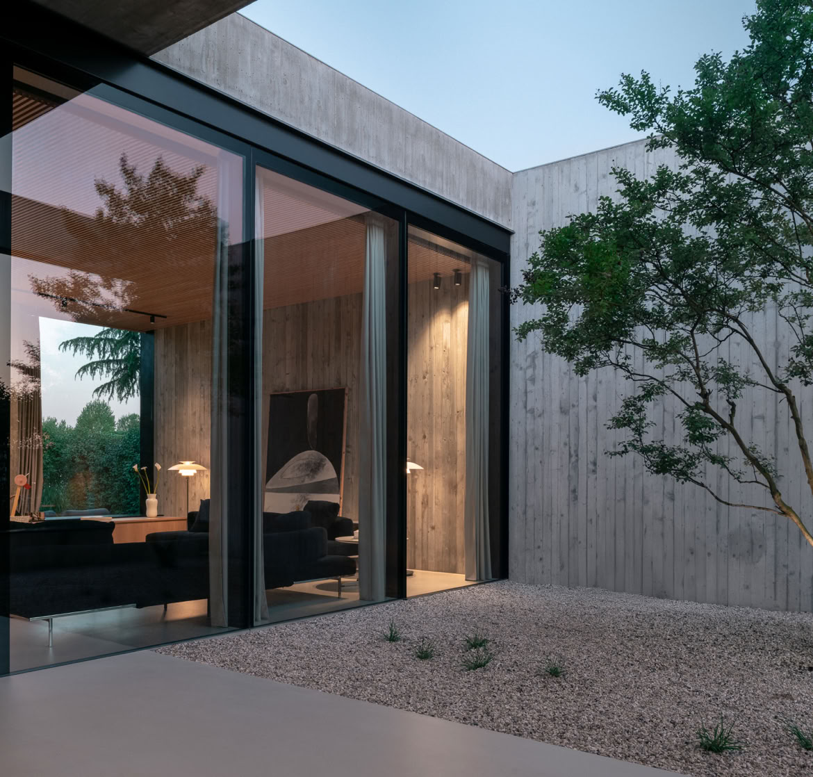 Elementi vegetali scelti con cura si insinuano tra i volumi in calcestruzzo, ammorbidendo la composizione architettonica.