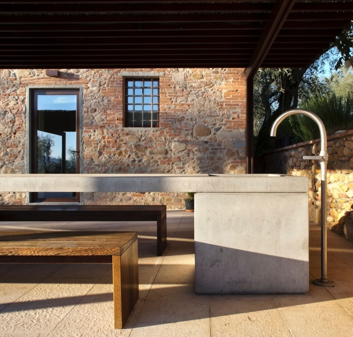 Shaded outdoor area with garden view, blending traditional Tuscan architecture and contemporary comfort.