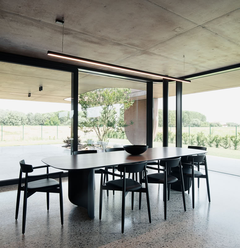 Dining area of the villa by MIDE architetti with large windows offering views of the spacious year-round usable portico.