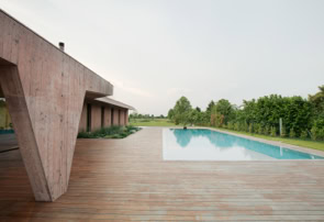 Spacious solarium with teak flooring and infinity pool opening onto lush green garden.