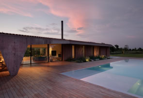 Sunset view of contemporary villa with swimming pool, emphasizing indoor-outdoor connection.
