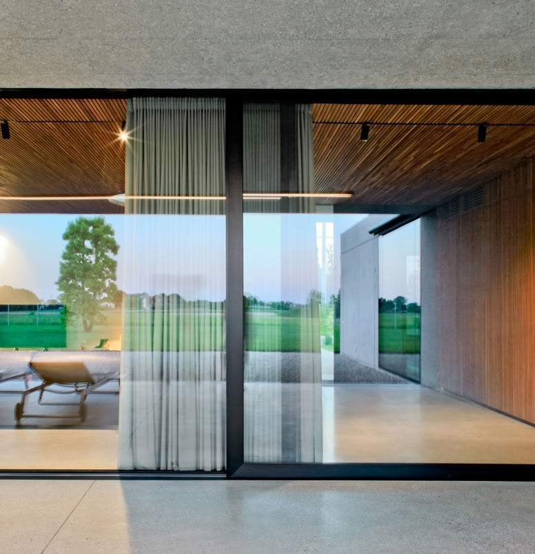 Single-story villa designed by MIDE architetti, featuring essential sandblasted concrete volumes and large glass walls facing the garden.