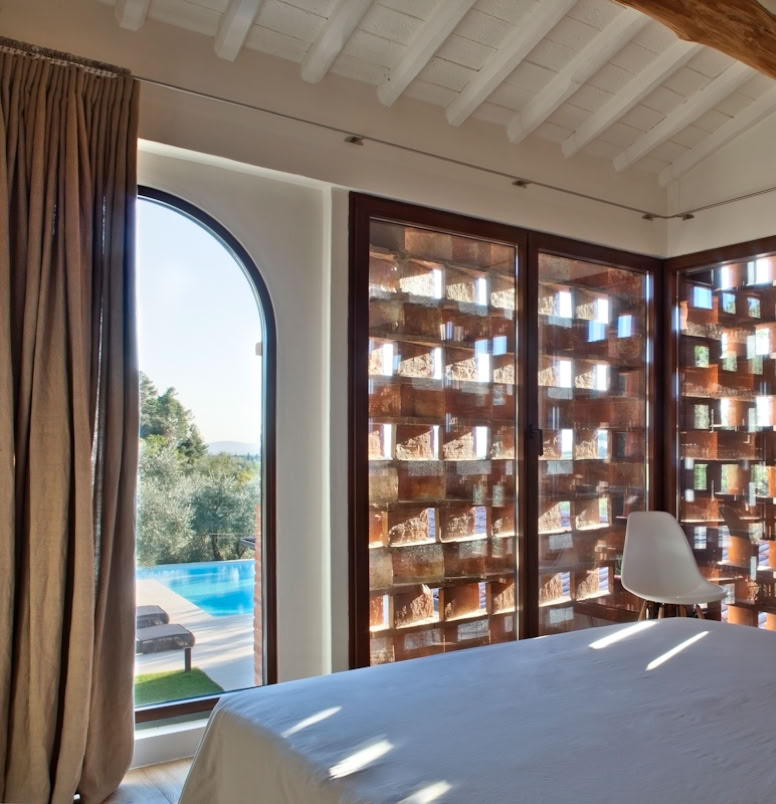 Large openings connecting interiors to garden and infinity pool, emphasizing continuity with the Tuscan landscape.