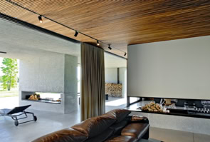 Open-plan living area with kitchen and lounge, oriented south and connected to the porch, extending the living space toward the greenery.