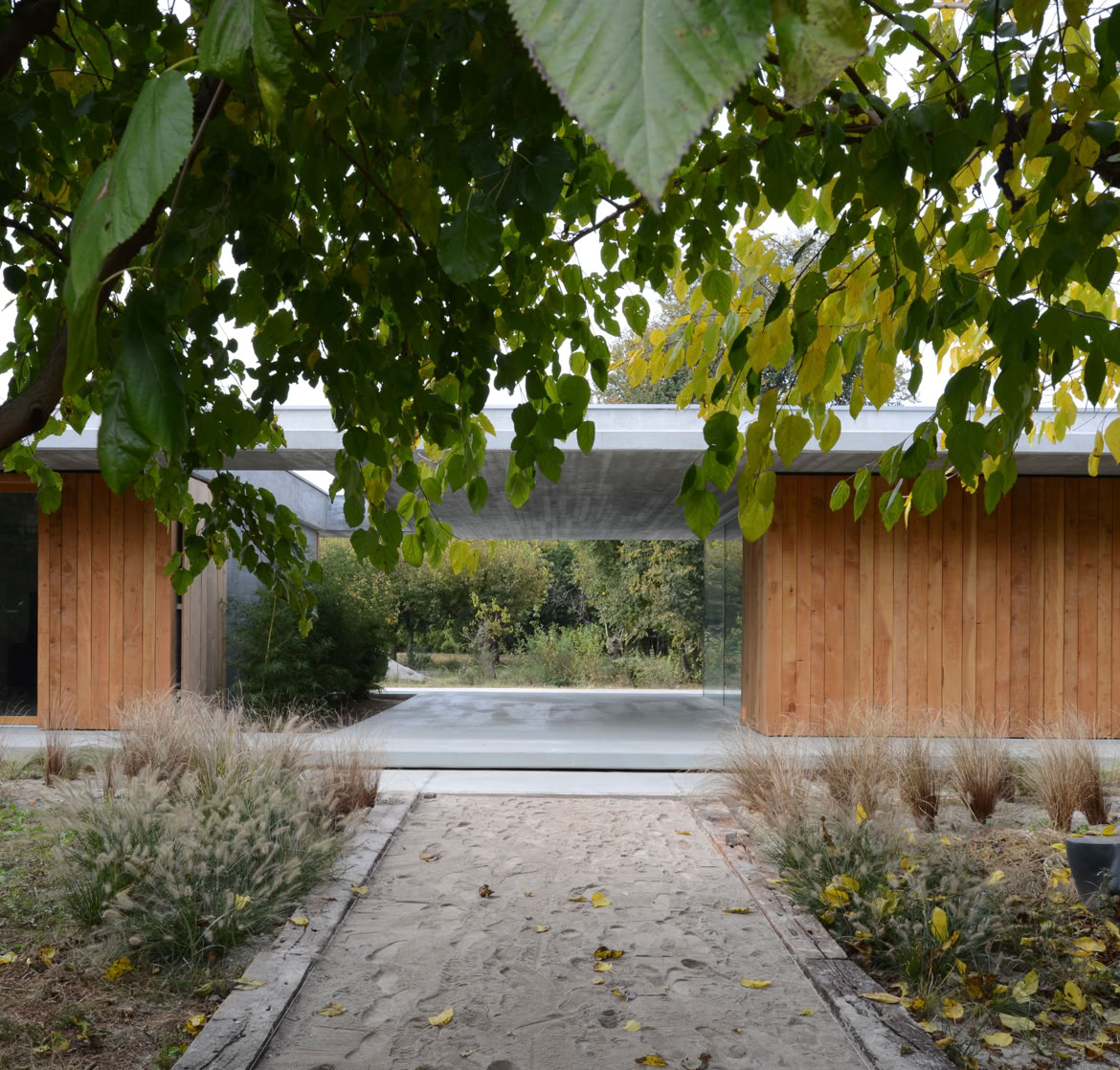External view of the single-family villa in Montebelluna, Treviso, surrounded by greenery, featuring clean horizontal lines and large windows.