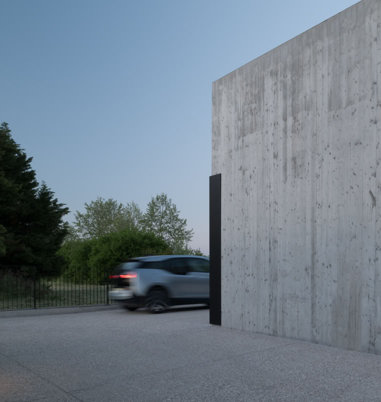 La matericità del calcestruzzo esposto definisce il carattere monolitico della villa, accentuando la semplicità formale e il forte legame con la luce naturale.