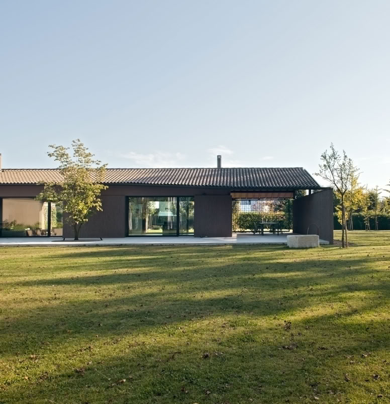 Contemporary villa in Noale reinterpreting Venetian rural architecture through natural light, tactile materials and landscape integration.