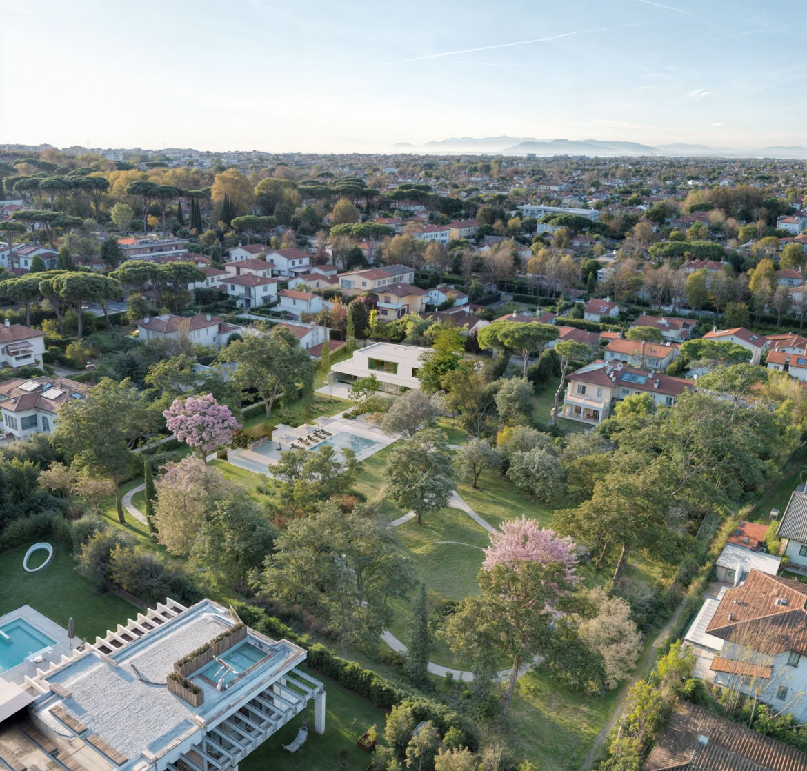 Aerial view of the contemporary villa in Forte dei Marmi by MIDE architetti, surrounded by lush greenery and featuring clean geometries that integrate harmoniously into the Tuscan coastal landscape.