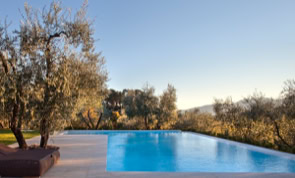 Piscina panoramica integrata nel giardino, pensata per godere del paesaggio naturale e della vegetazione mediterranea.