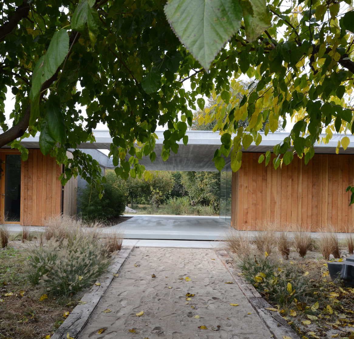Contemporary residence in Montebelluna, Treviso, immersed in greenery. Single-level design with wood cladding, large windows, open living spaces, and a seamless connection between interior and exterior.
