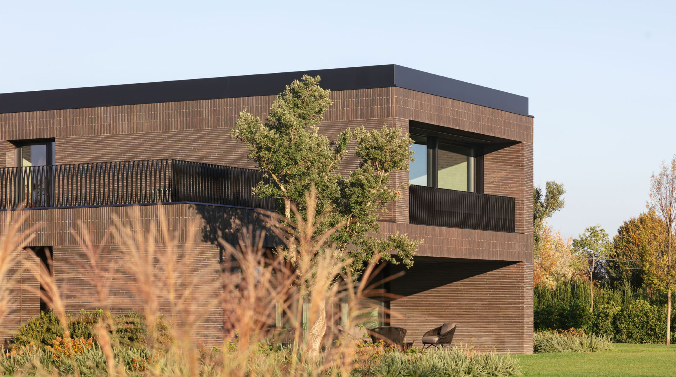 View of the main façade of the brick villa in Veneto, featuring a large terrace overlooking the private park.