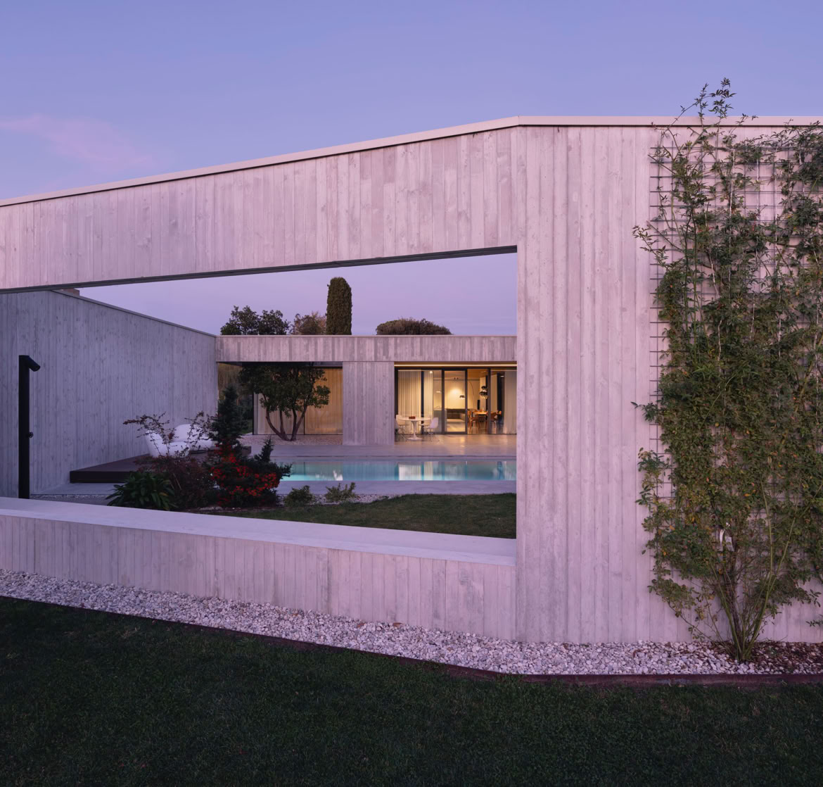 Evening view of the outdoor pool at the Piave villa designed by MIDE architetti, highlighting the integration of water, architecture, and natural surroundings.