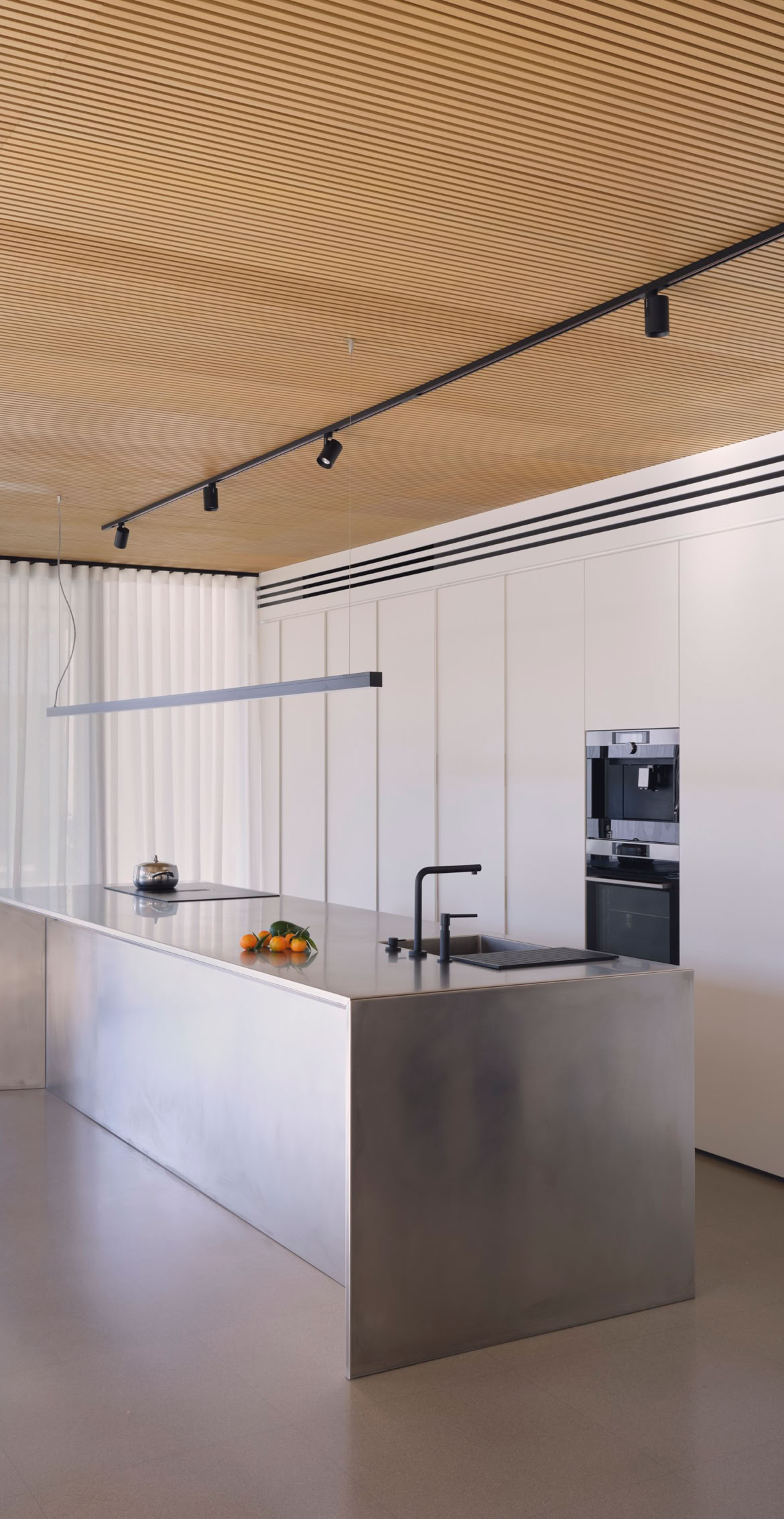 Un'isola della cucina in acciaio è posta al centro di un ampio open space, progettato da MIDE architetti in questa villa in provincia di Venezia.