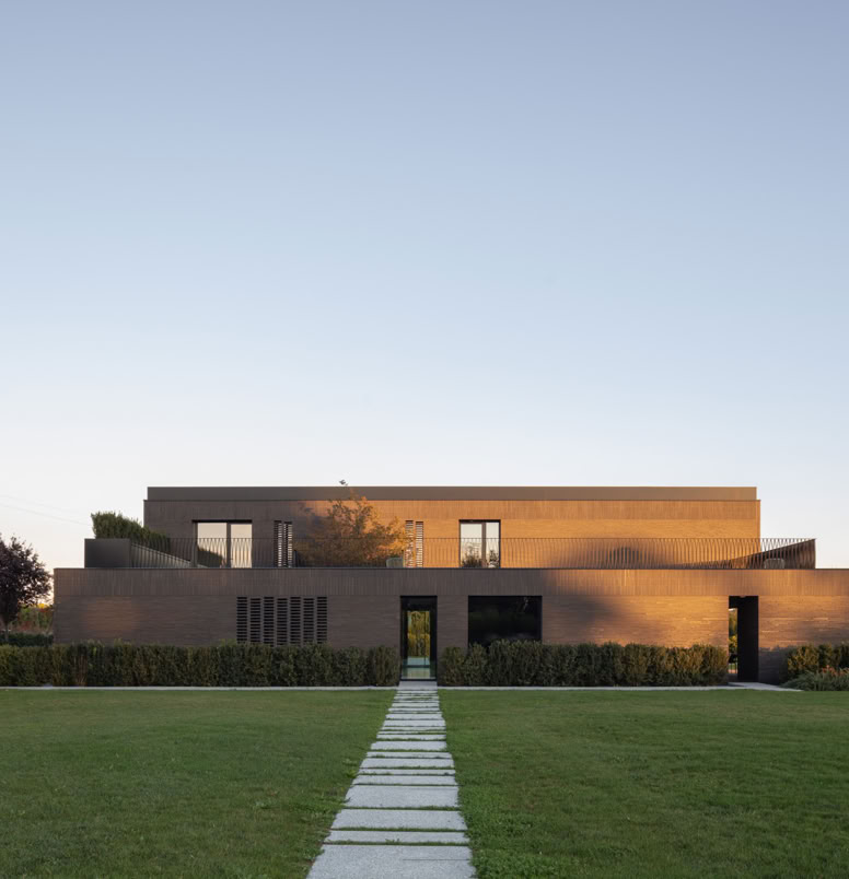 Contemporary brick villa by MIDE architetti featuring panoramic terrace, large windows, open-plan living, and refined interiors. A harmonious dialogue between architecture, light, and landscape