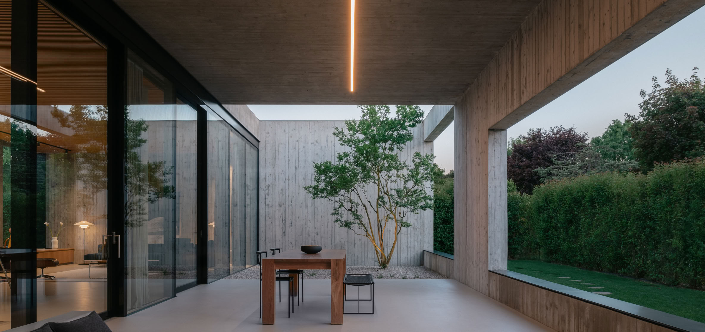 Contemporary single-family house designed by MIDE architetti, blending exposed concrete and natural wood. Open-plan living, central patio, and seamless connection with nature and garden.
