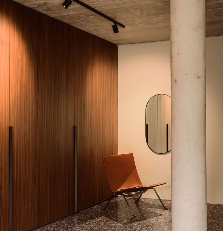 View of a service area featuring custom-built cabinetry and a concrete column in the brutalist house designed by MIDE architetti.